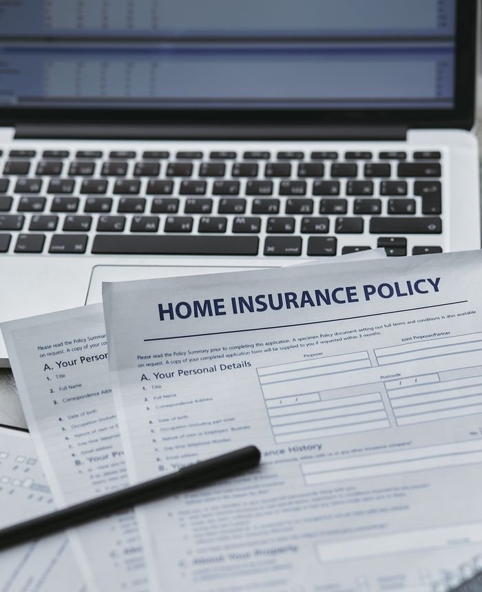 about-06 Close-up of home insurance documents with a laptop, symbolizing modern paperwork processes.